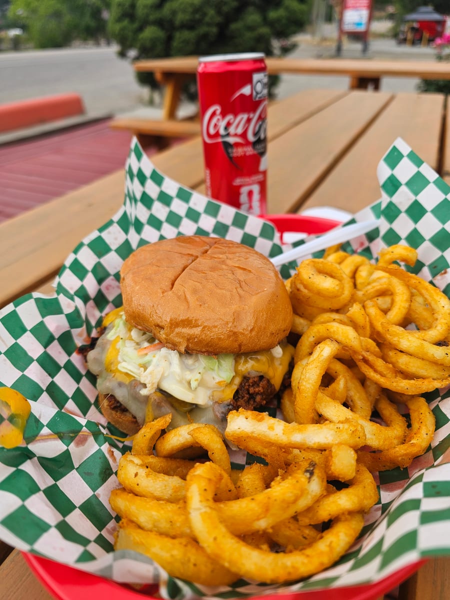 A Deluxe Joe and curly fries in a checkered basket with a cold Coke